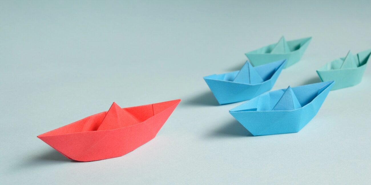 Entrada artículo blog bajo el título "Responsabilidad social y desarrollo sostenible" | imagen de barcos de papel en diferentes colores siguiendo al líder
